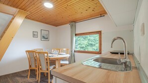 A kitchen with a wooden ceiling, a dining table with chairs, a window with a view, and a sink. - Lodge Trtinka /w Terrace & BBQ in Nature, Žalec, Slovenia (Žalec)