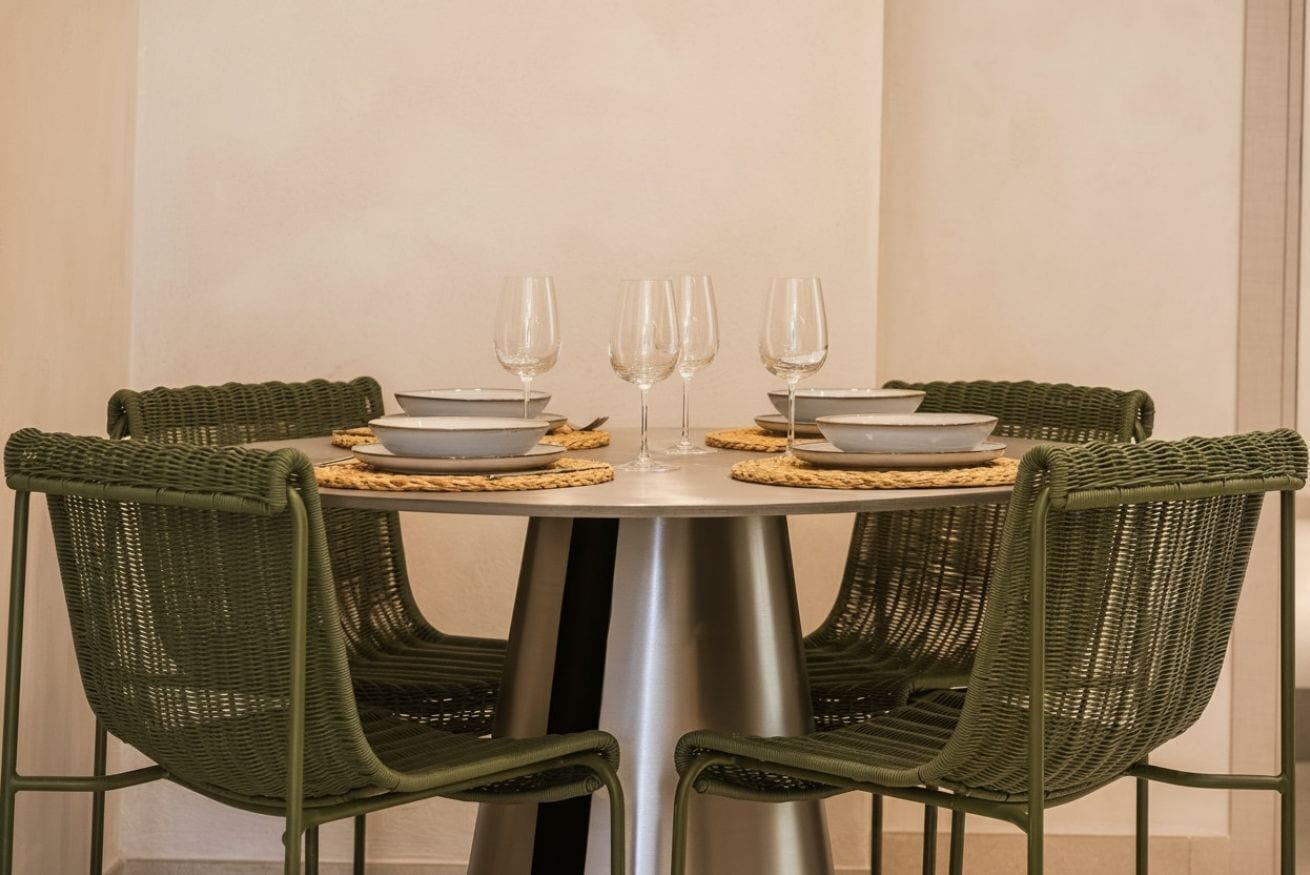 A round table with four chairs, each with a woven placemat.