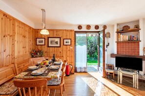 A dining area with wooden walls, a table set with plates, glasses, and a bouquet of flowers. - Family Apartment Steps From Ski Lifts, Courmayeur, Italy (Courmayeur)