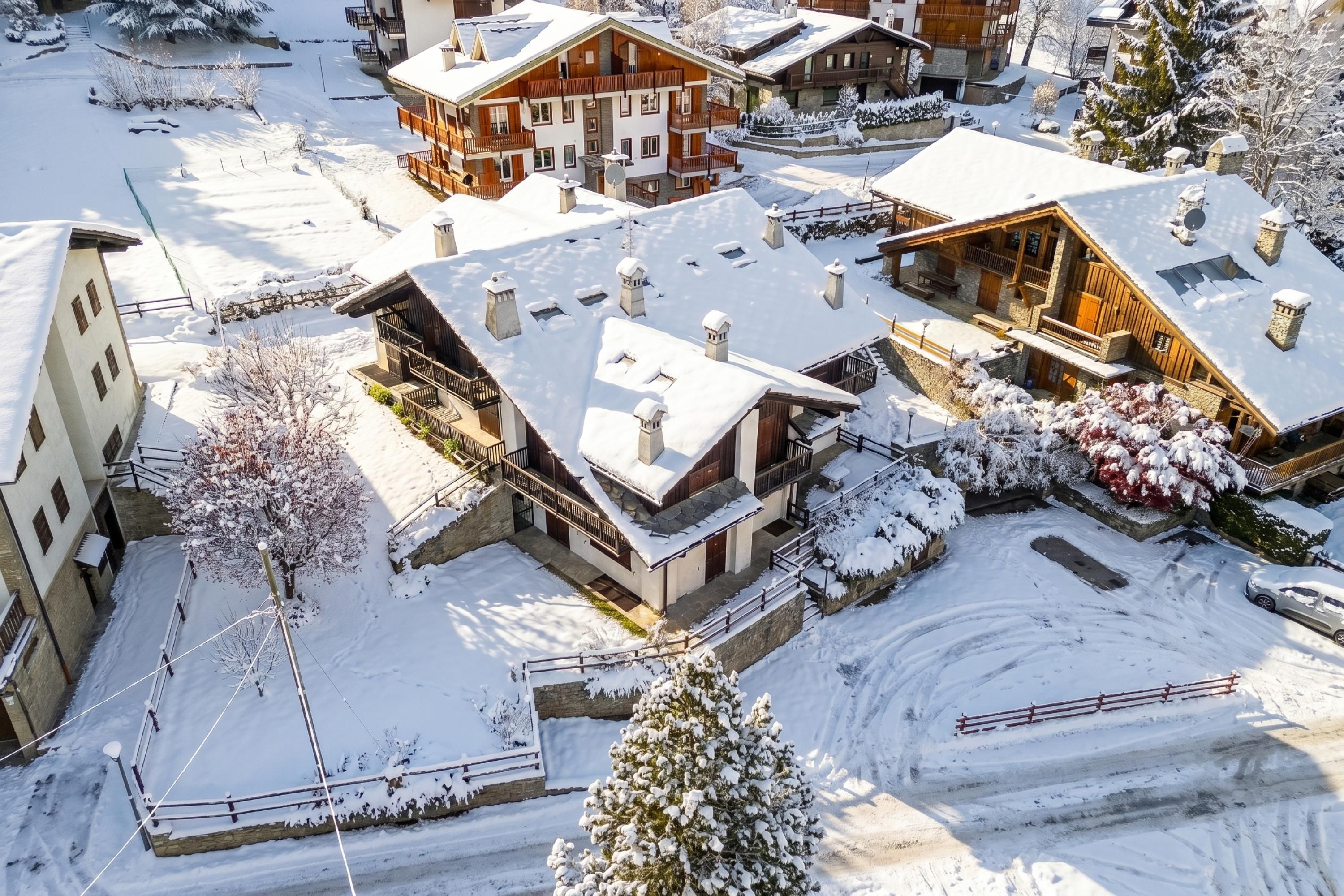 A snow-covered residential area with multiple houses featuring balconies and wooden exteriors.