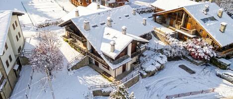 A snow-covered residential area with multiple houses featuring balconies and wooden exteriors.