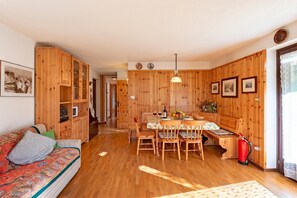 A wooden interior with a sofa, dining table, chairs, and a fire extinguisher. - Family Apartment Steps From Ski Lifts, Courmayeur, Italy (Courmayeur)
