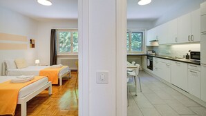 A modern hotel room with two beds, a kitchenette, and a view of trees through the window. - 76 The Lake House Sole, Melide, Switzerland (Melide)