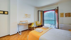 A hotel room with a bed, a desk, a chair, and a balcony with a view. - 76 The Lake House Sole, Melide, Switzerland (Melide)