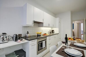 A modern kitchen with white cabinets, a stainless steel oven, and a breakfast setup with fruits and bread. - 76 The Lake House Saturno, Melide, Switzerland (Melide)