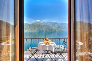 Ein Balkon mit Frühstückstisch, mit Blick auf einen See und Berge.