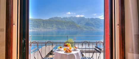 Una tavola imbandita con cibi per la colazione e vista su un lago e montagne.