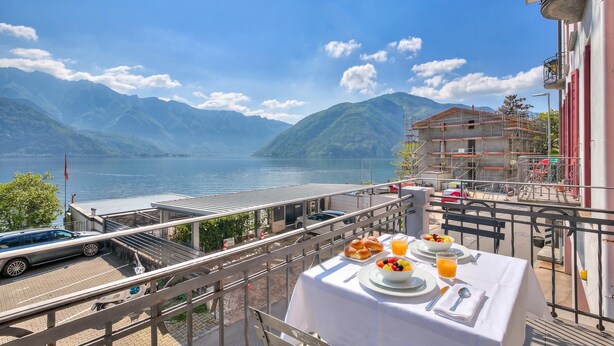 Un balcon avec une table dressée pour le petit-déjeuner, donnant sur un lac et des montagnes.