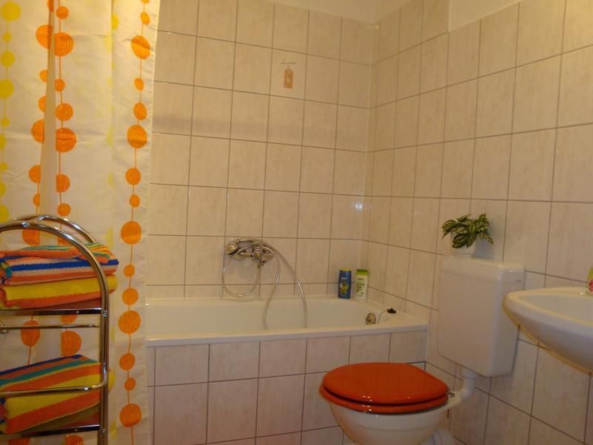 Baño con bañera, inodoro y repisa con toallas.