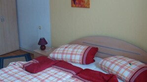 Ein Schlafzimmer mit einem Bett, Kissen, einer Lampe und Kunstwerken an der Wand.