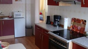 Eine kompakte Küche mit Mikrowelle, Kaffeemaschine und einer Kaffeepackung.
