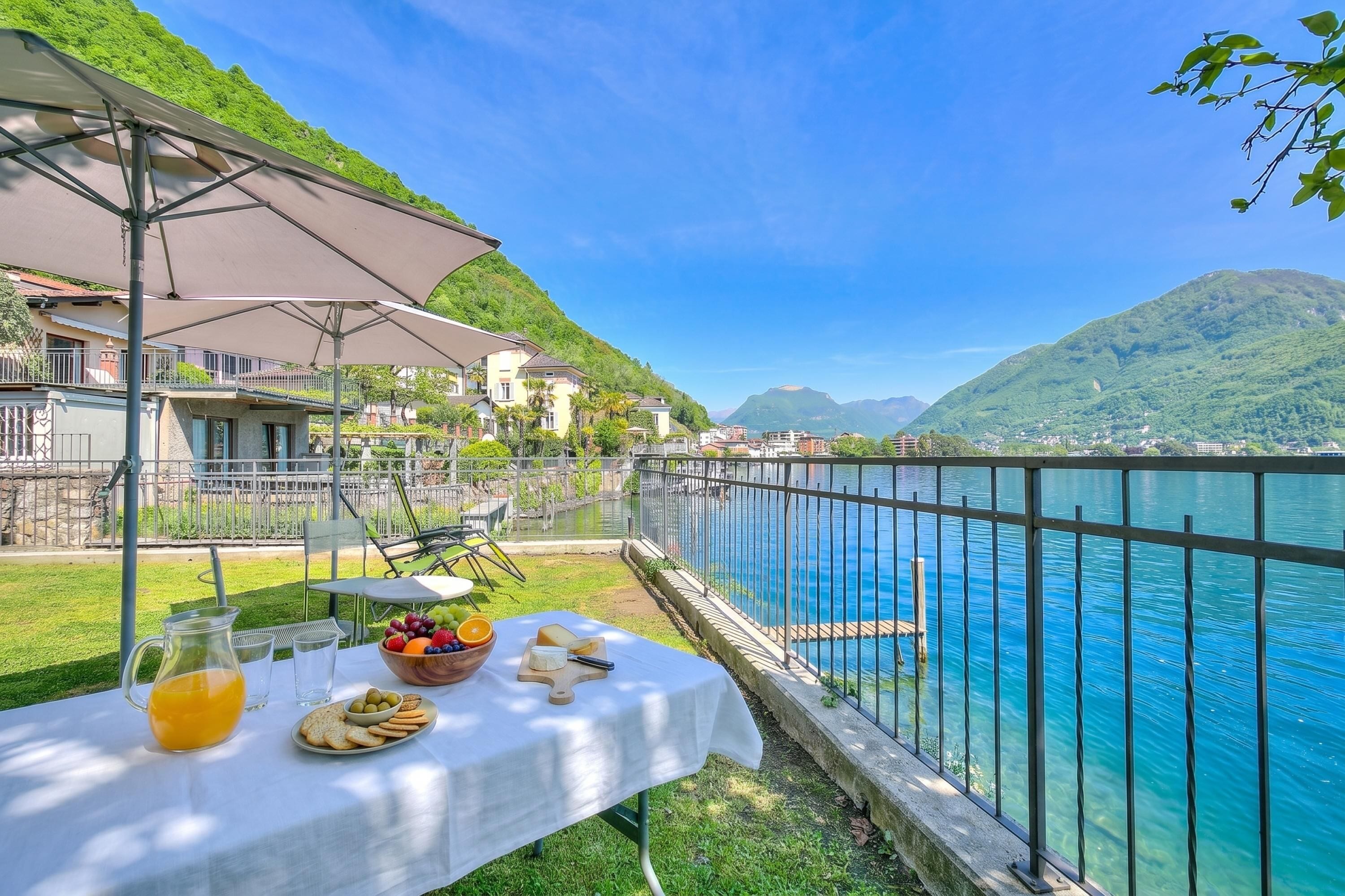 A table with food and drinks, a view of a lake, and a mountain in the background.
