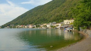 Une ville située au bord d’un lac, avec des bâtiments qui longent la rive, un quai et une colline.