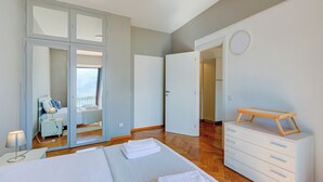 Une chambre à coucher avec un lit, une commode, un miroir et une vue sur le balcon.
