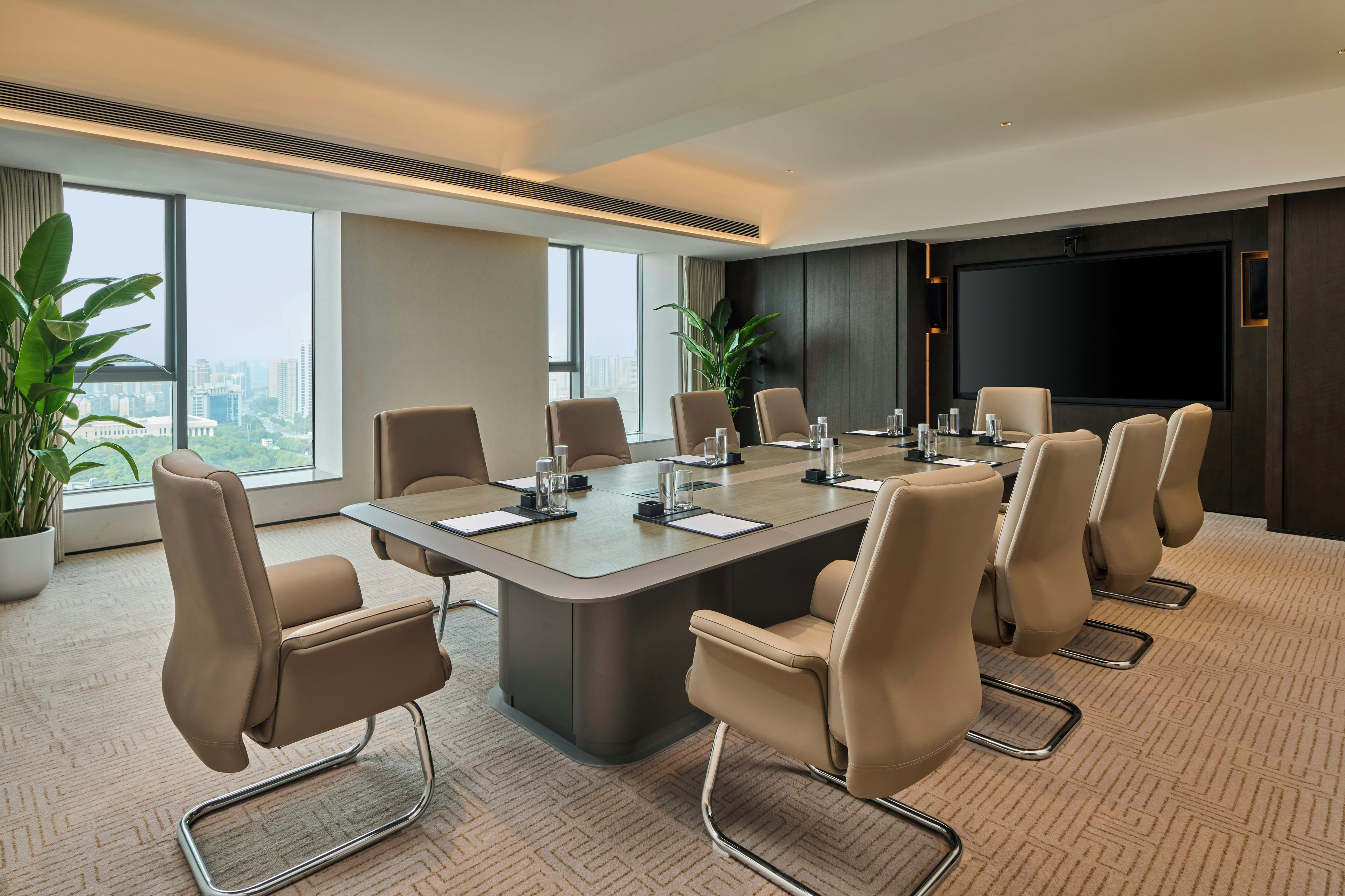 Uma sala de conferências moderna com uma mesa grande, cadeiras e uma tela de projeção.