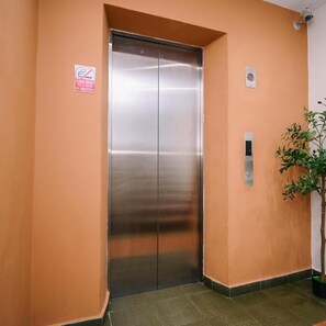 A metallic elevator door in a hallway with a 'No Smoking' sign and a potted plant. - Swing & Pillows @ Sunway Pyramid PJ (Petaling Jaya)