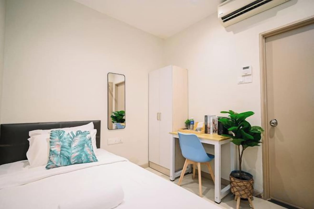 Une chambre d’hôtel équipée d’un lit, d’un bureau, d’une chaise, d’un miroir, d’une armoire et d’une plante en pot.