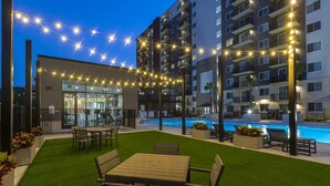 Ein Hotel mit Pool, Sitzgelegenheiten im Freien und Lichterketten.