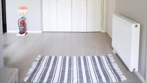 A hallway with a striped rug, a white radiator, and a fire extinguisher. - GREY HOUSE NISEKO (Niseko)