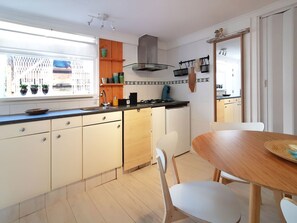 Ett modernt kök med ett fönster, träskåp, en spis och en matplats.