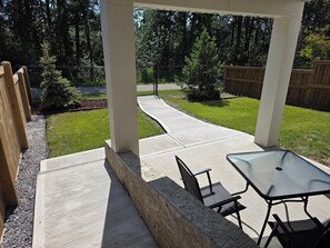 Un patio techado con piso de concreto, una mesa y sillas.