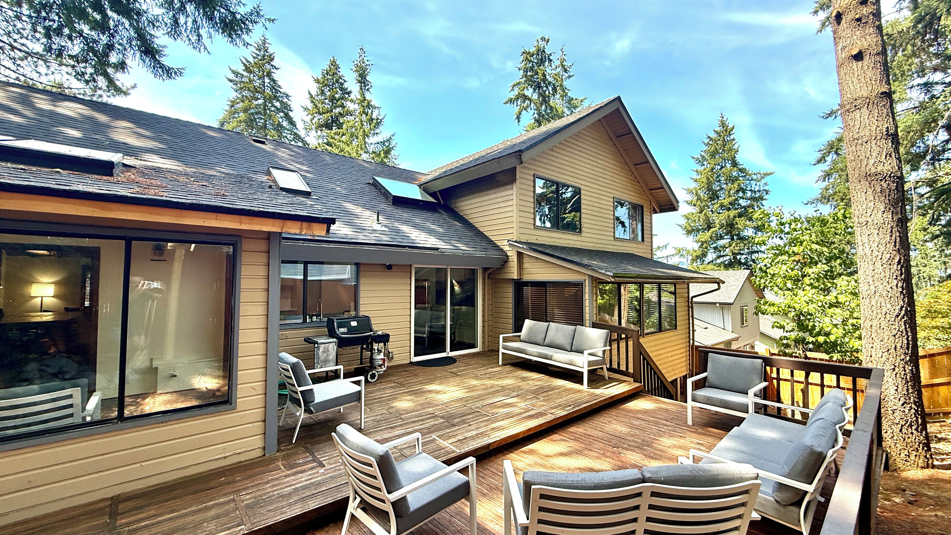A two-story house with a deck, outdoor furniture, and a sliding glass door.