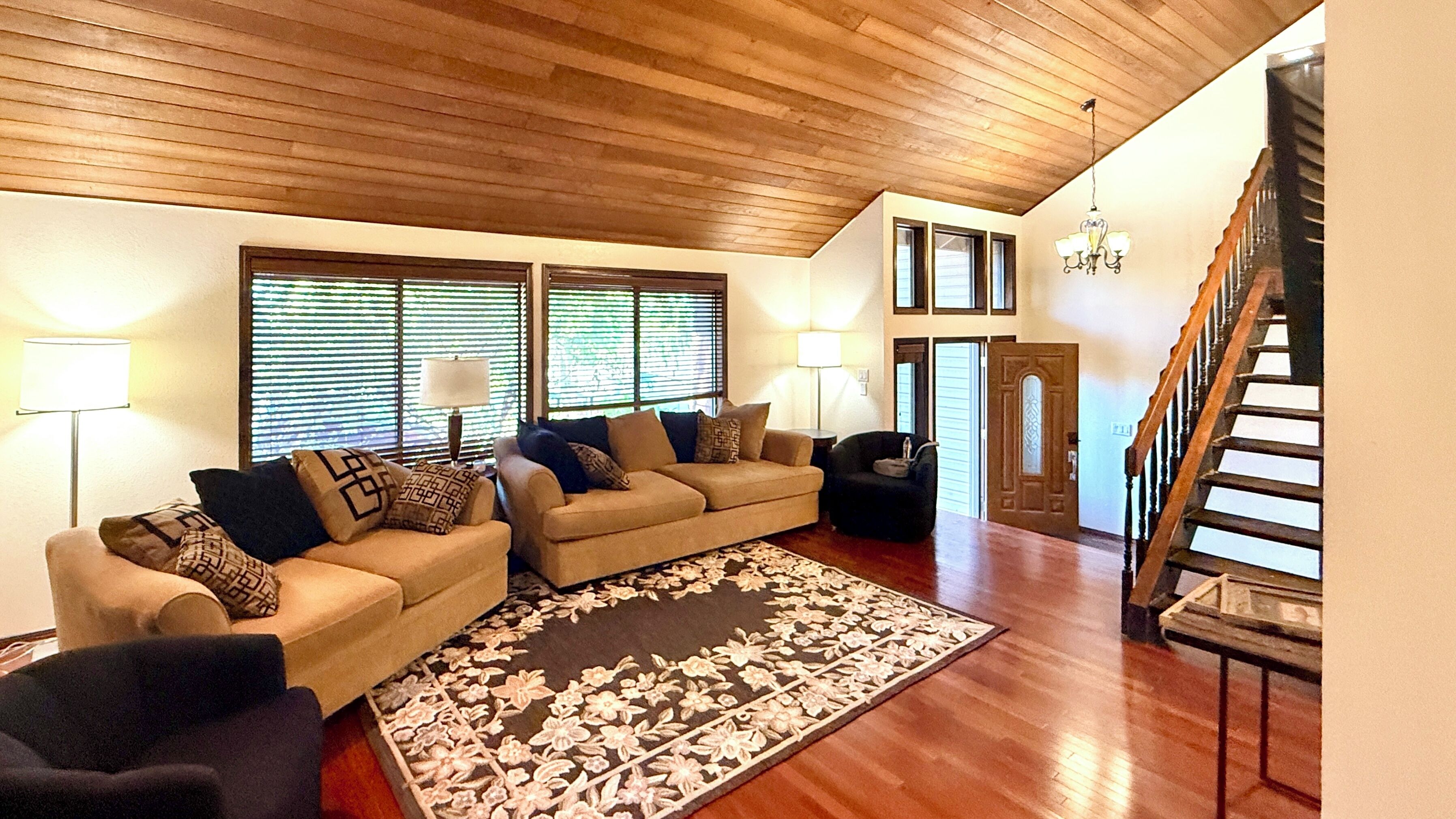 A living room with two sofas, a rug, and a staircase.
