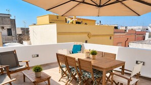 A rooftop terrace with a wooden table and chairs, a potted plant, and a large umbrella. - Camera Osanna by Symphonya Rentals (Nardò)
