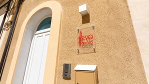 A building facade with a beige textured wall, a white door, and a sign that reads 'Evo Nardo'. - Camera Osanna by Symphonya Rentals (Nardò)