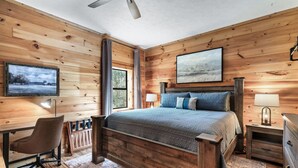 Un dormitorio con cama de madera, escritorio, silla y ventilador de techo.