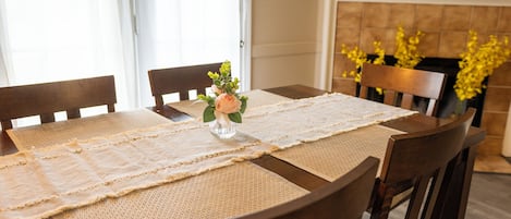 A dining table with a placemat, chairs, and a vase with flowers.