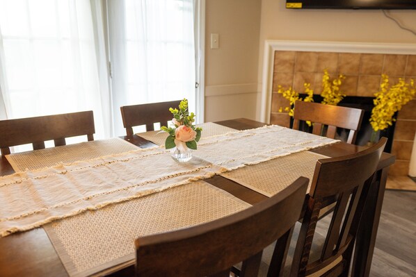 A dining table with a placemat, chairs, and a vase with flowers.