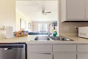 A kitchen with a dishwasher, double sink, and a ceiling fan.