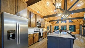 A modern kitchen with wooden cabinetry, stainless steel appliances, and a large island. - Gnarly Ever After | Luxury Meets Fun (Broken Bow)