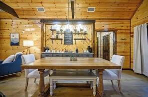 Ein Holzinterieur mit einem Esstisch, Stühlen, einer Bank, einer Kaffeestation und einem gerahmten Bild an der Wand.