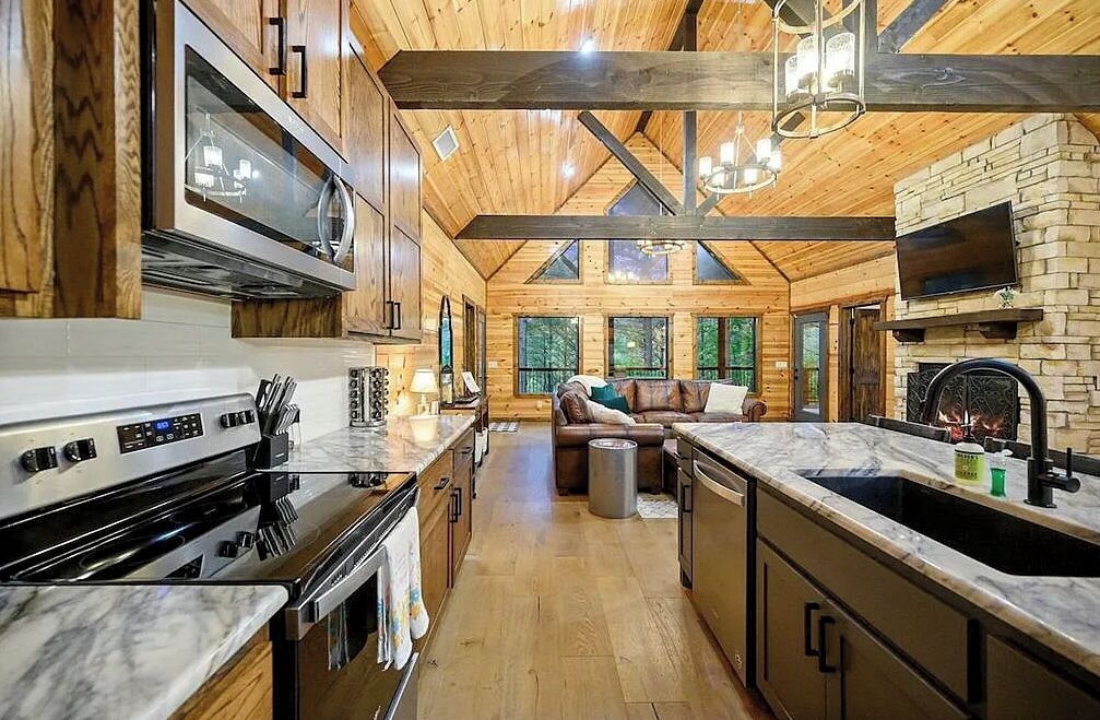 A modern kitchen with a large stove, microwave, and a stone fireplace.