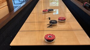 A shuffleboard table with numbered scoring areas and pucks. - Gnarly Ever After | Luxury Meets Fun (Broken Bow)