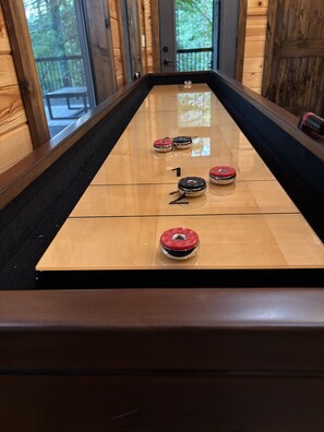 Ein Shuffleboard-Tisch mit nummerierten Spielfeldern und Spielsteinen.