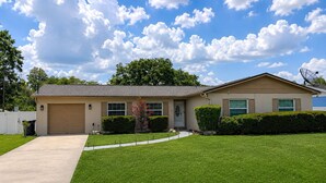 A single-story house with a garage, a well-maintained lawn, and a clear blue sky with clouds. - Family-Friendly 2-bedroom 2-bath house close to Tampa Airport (Tampa)