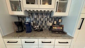 A kitchen with white cabinets, a coffee maker, a tea set, and a sign reading 'Tastefully British.' - Family-Friendly 2-bedroom 2-bath house close to Tampa Airport (Tampa)