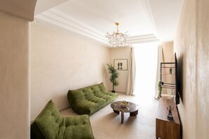 Ein Wohnzimmer mit einer Couch, einem Couchtisch und einem an der Wand montierten Fernseher.