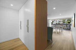 Un interior moderno con un separador de madera, paredes blancas y un comedor con vistas al exterior.