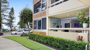 Een meerlaags gebouw met een balkon, oprit en een verzorgd gazon.