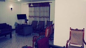 A living room with a sofa, armchairs, a TV, and a ceiling fan. - A&A Homestay (Seeduwa)