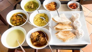 A table with various dishes including curries, rice, and flatbreads, suggesting a meal setup in a dining area. - A&A Homestay (Seeduwa)