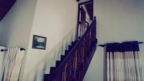 A staircase with wooden railings, a picture on the wall, and a window with curtains. - A&A Homestay (Seeduwa)