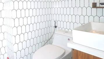 A bathroom with a toilet, a sink, and a shower area.