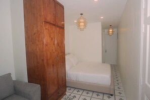 A bedroom with a wooden wardrobe, a bed with white bedding, and a patterned floor. - Lai Hotel Phu Nhuan - Near Tan Dinh Church & District 1 (Ho Chi Minh City)