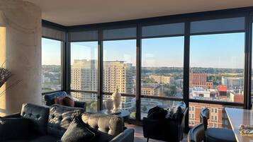 A modern living room with a large window, a sofa, a coffee table, and a chair.