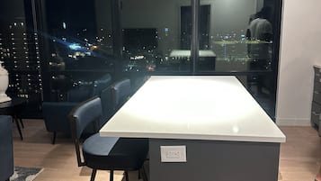 A modern kitchen with a large island, a dining area with chairs, and a view of the city at night.